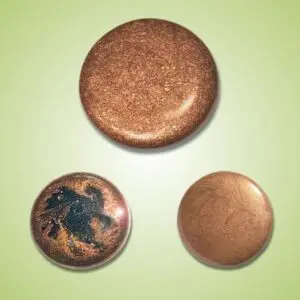 Three round copper objects with varying textures and colors on a light green background.